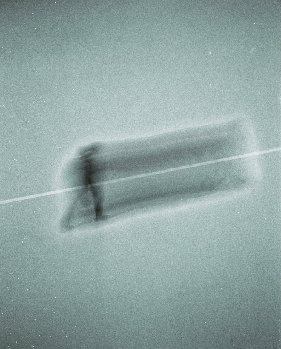 A running figure smeared into a horizontal trail by a long exposure, cold grey-green