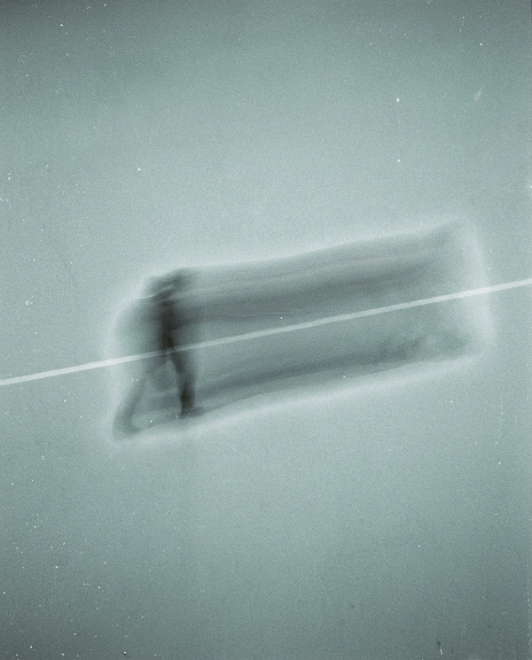 A running figure smeared into a horizontal trail by a long exposure, cold grey-green
