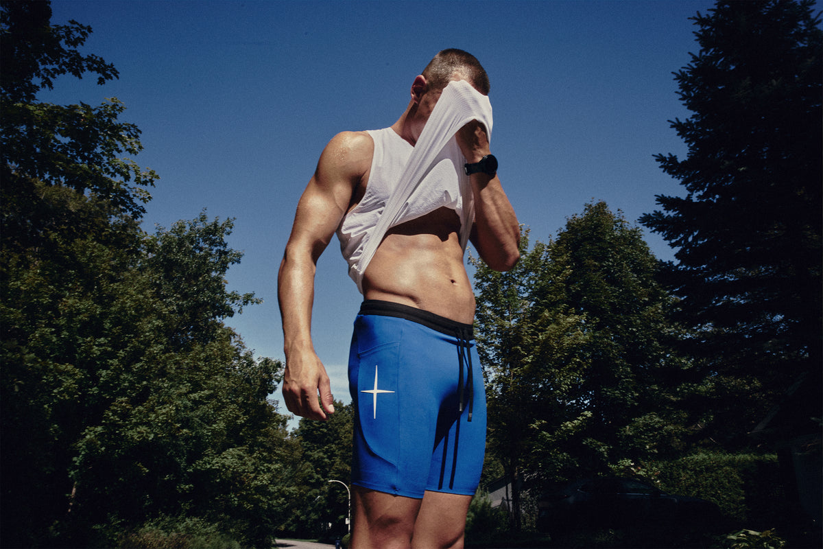 Model outdoors in blue running half tights, lifting a white T-shirt